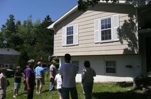 image of a group of 9 course participants standing outside of two story house on a sunny day